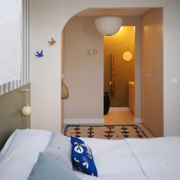 a bed with white sheets and blue pillows in a small room next to a doorway