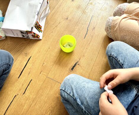 two people sitting on the floor next to each other with their feet crossed and one person holding a pen