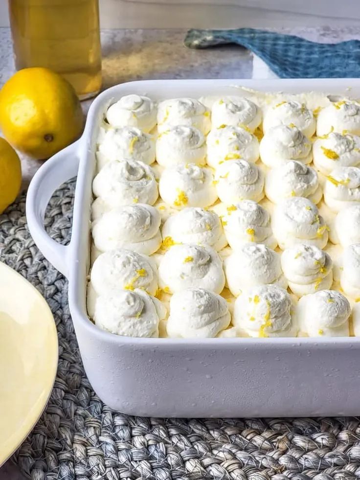 a pan filled with lemon meringue on top of a table next to sliced lemons