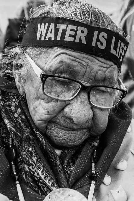 an old woman wearing glasses and a headband with the words water is life on it