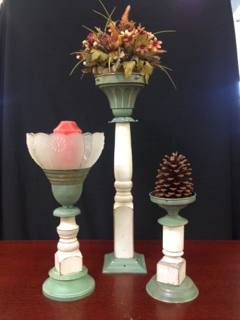 three vases with flowers and pine cones in them on top of a wooden table