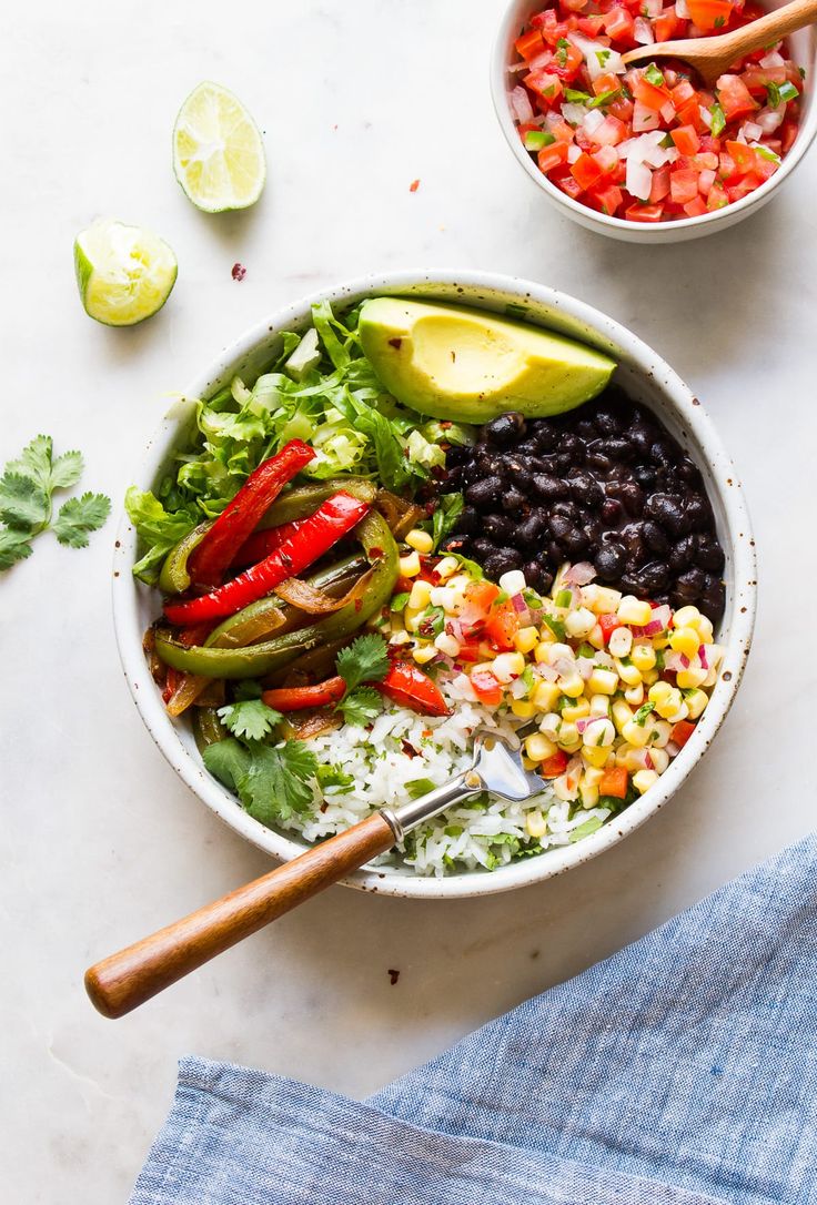 two bowls filled with different types of food next to limes and cilantro