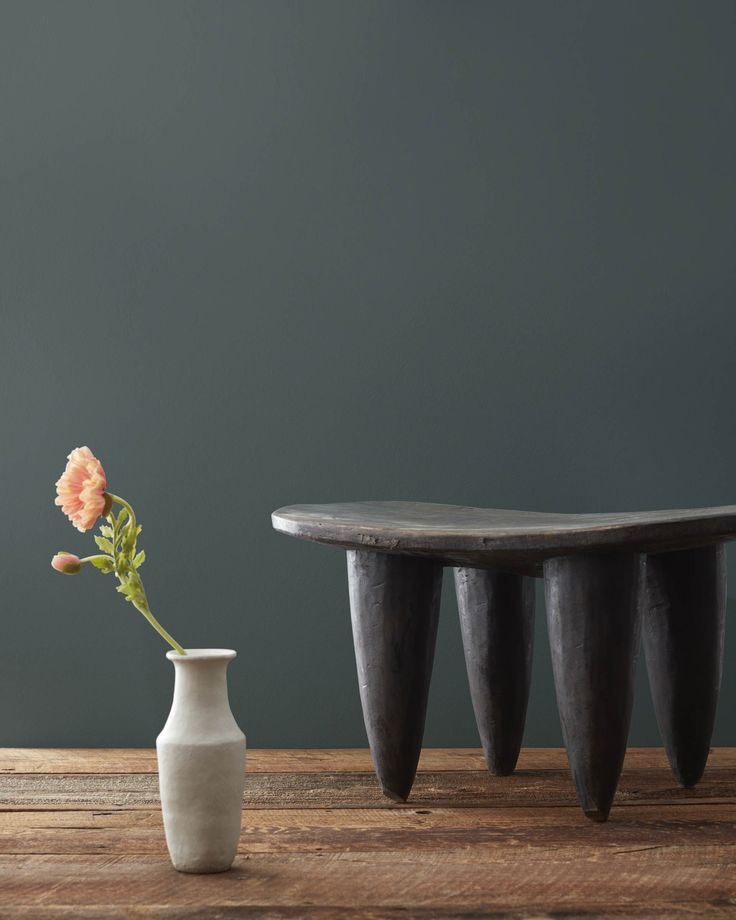 a white vase sitting on top of a wooden table next to a small flower pot