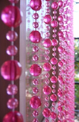 pink beads hanging from the side of a window