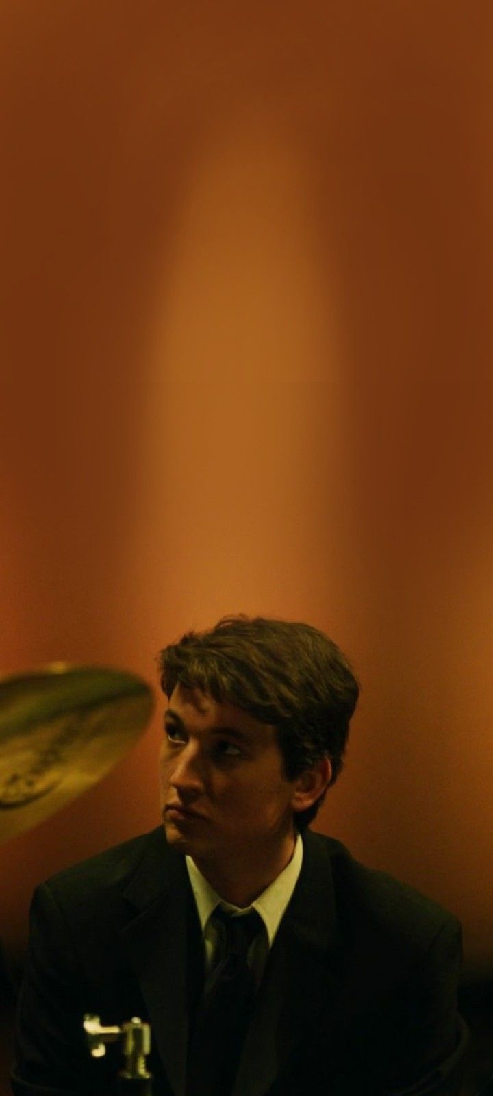 a man in a suit and tie playing drums