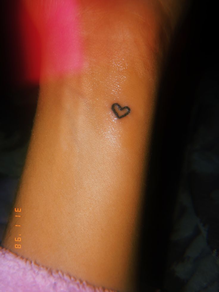 a small heart tattoo on the left side of the ankle, which is black in color