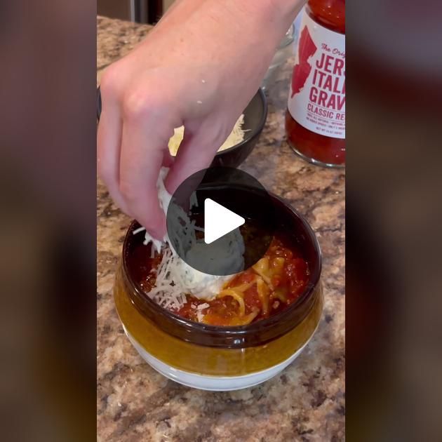 a person is adding cheese to a bowl of pasta