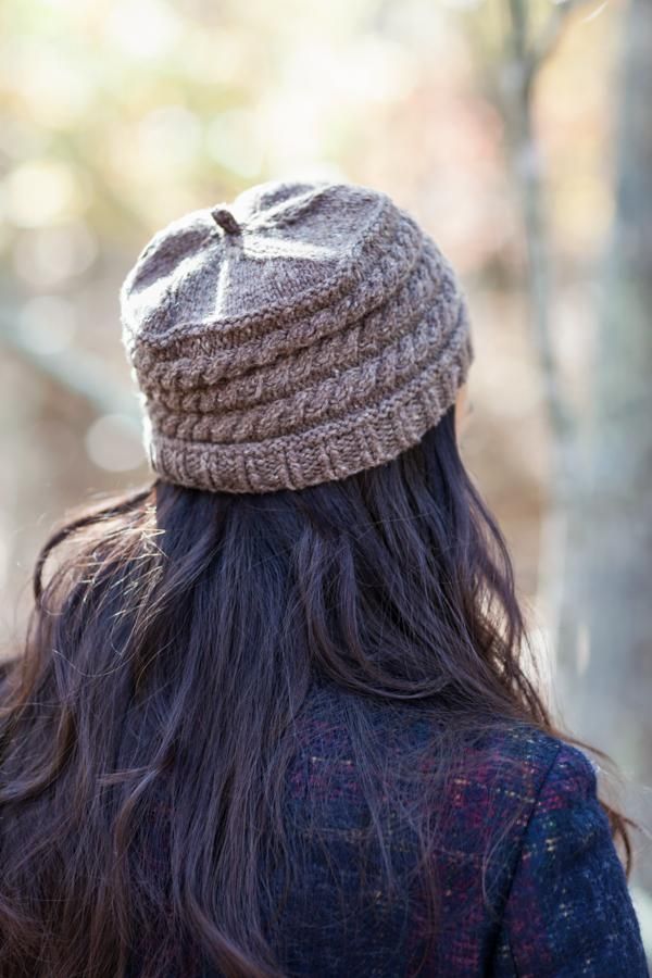 the back of a woman's head with long hair wearing a knitted hat