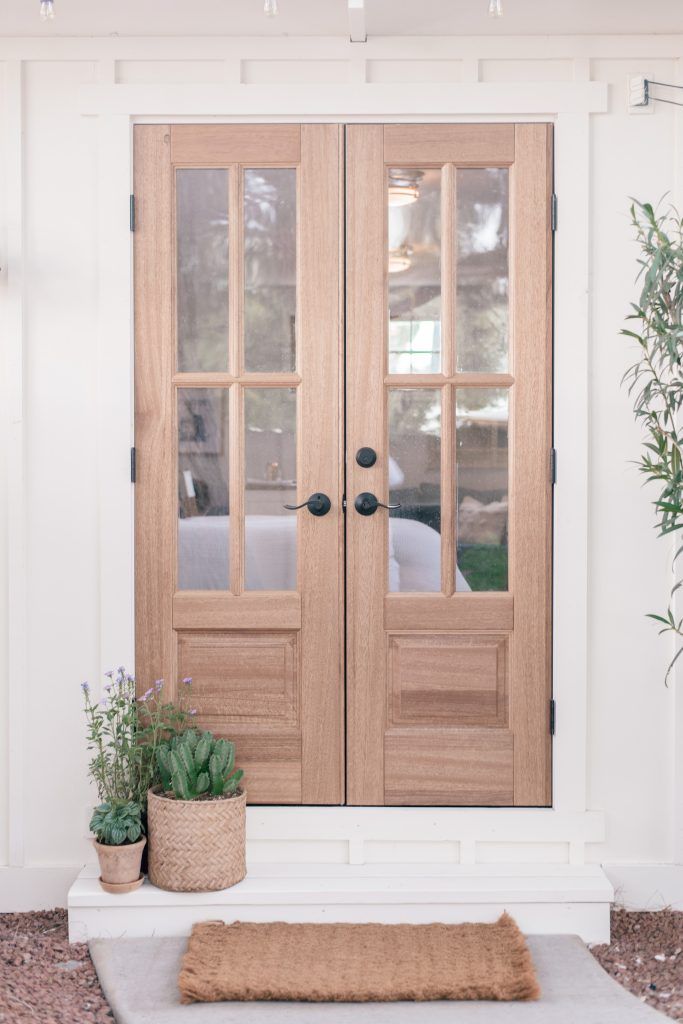 the front door to a house with two potted plants and a rug on the ground