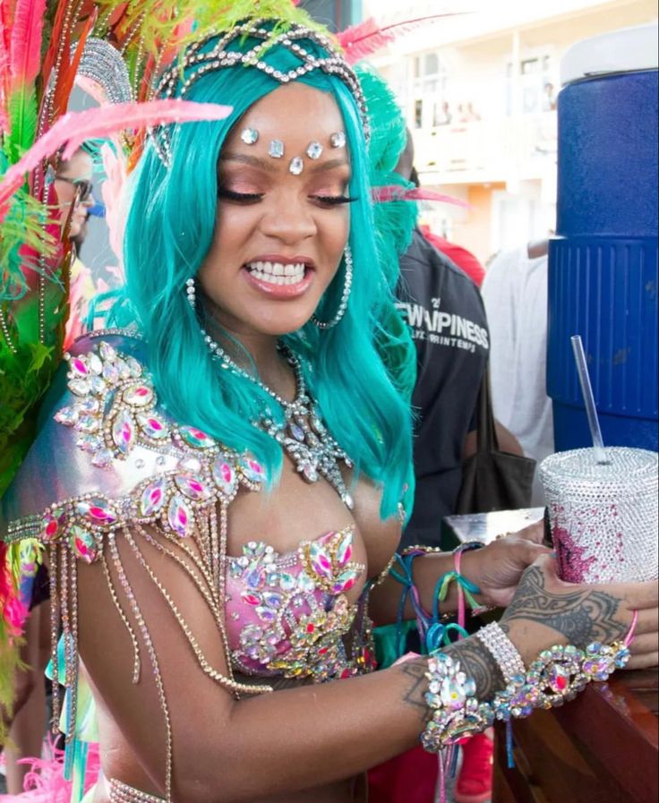 a woman with blue hair and green wig holding a drink in her hand while standing next to other people