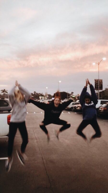 three people jumping in the air with their hands up and one person holding his arms out