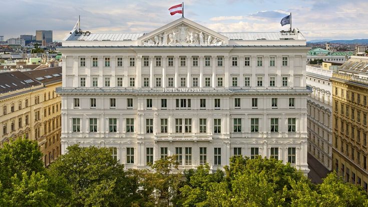 a large white building with many windows on top of it's roof and trees in the foreground