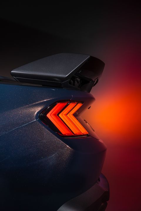 the back end of a blue car with an orange tail light