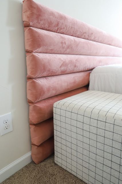 a bed that is made up to look like a headboard with pillows on it