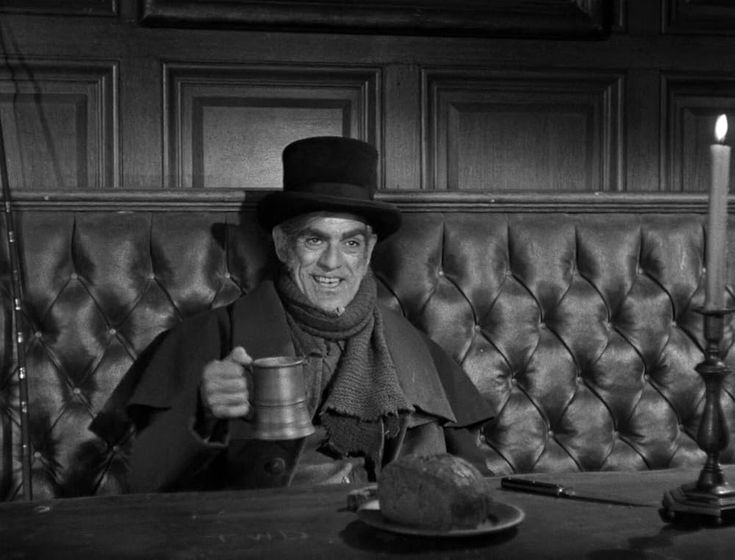 a man sitting at a table with a cup in his hand and a candle in the other hand