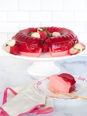 a strawberry cheesecake on a cake plate with a slice cut out and ready to be eaten