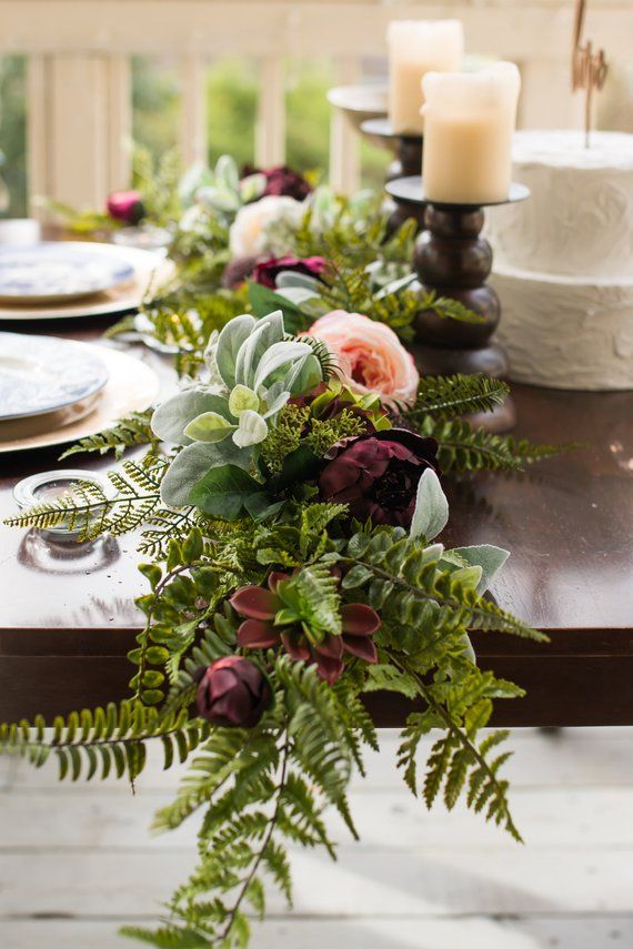 the table is set with candles, plates and flowers in vases on top of it