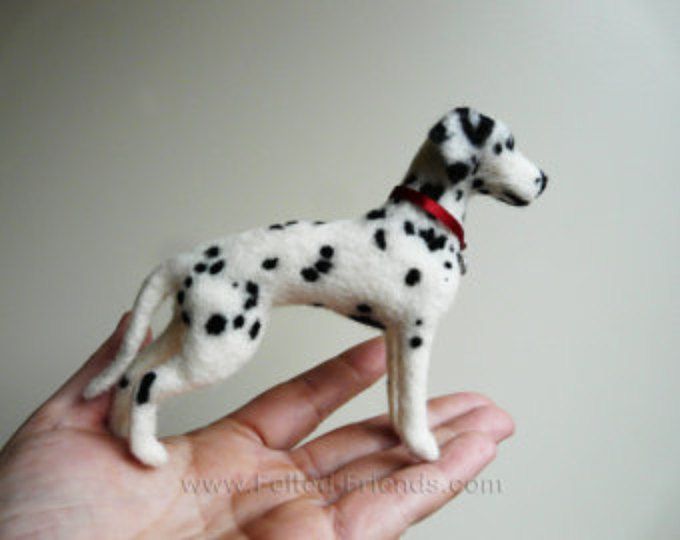 a hand holding a miniature dalmatian dog in it's palm