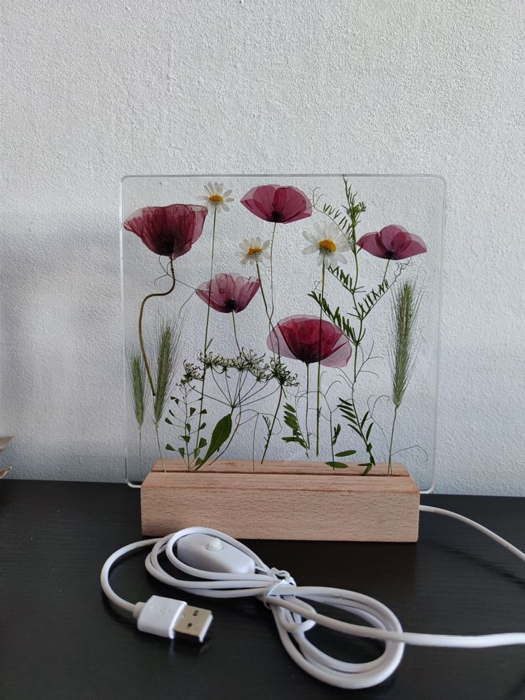 an acrylic glass block with flowers on it sitting next to a charger