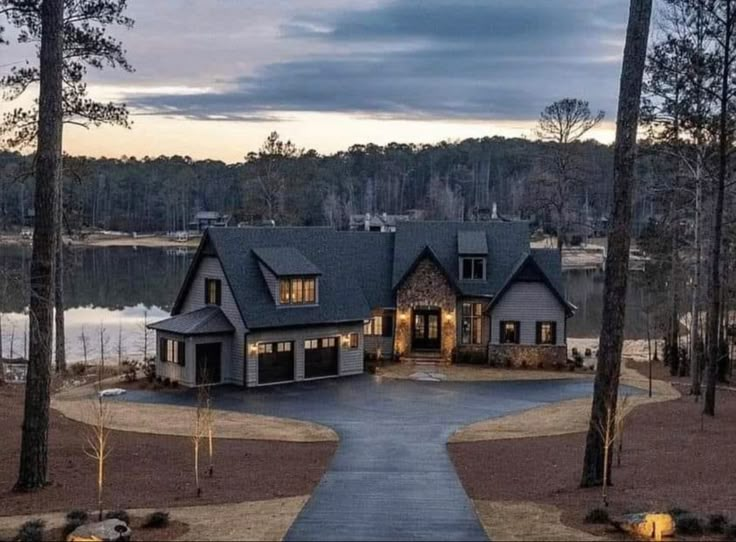 a large house sitting on top of a lush green field next to a lake at dusk