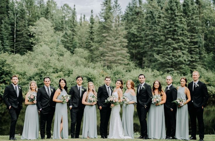 a group of people standing next to each other in front of trees and water with flowers