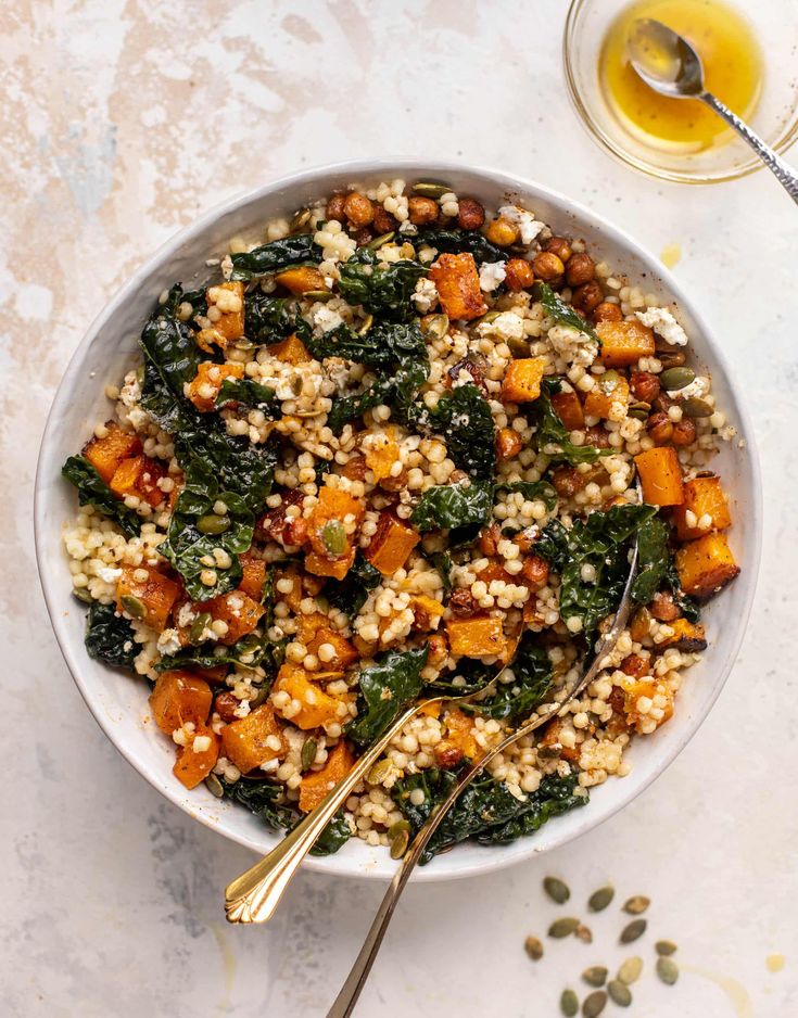 a bowl filled with rice and vegetables on top of a white table next to a glass of orange juice