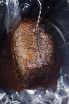 a piece of meat sitting on top of foil in a bowl with tongs sticking out of it