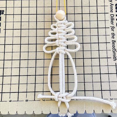 an ornament made out of rope on top of a piece of paper next to a ruler