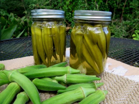 two jars filled with pickles sitting on top of a table