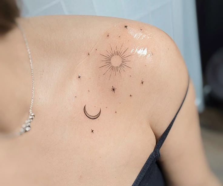 a woman with a sun and moon tattoo on her upper arm, behind her shoulder