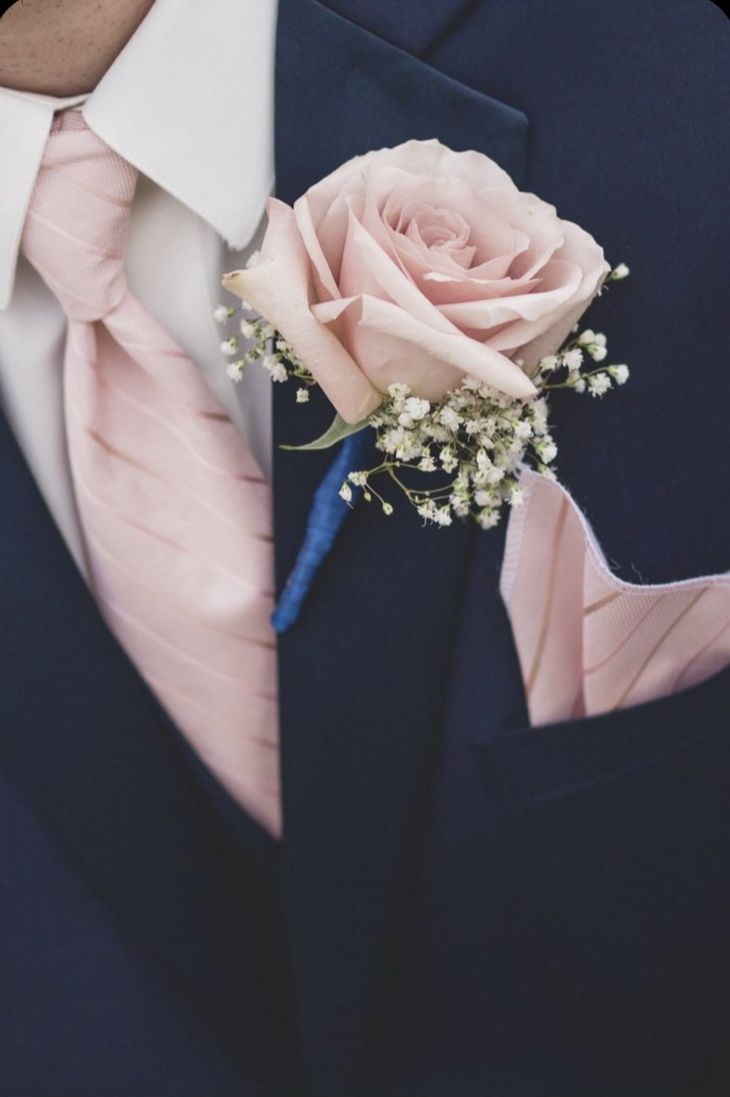 a man in a blue suit with a pink rose boutonniere on his lapel