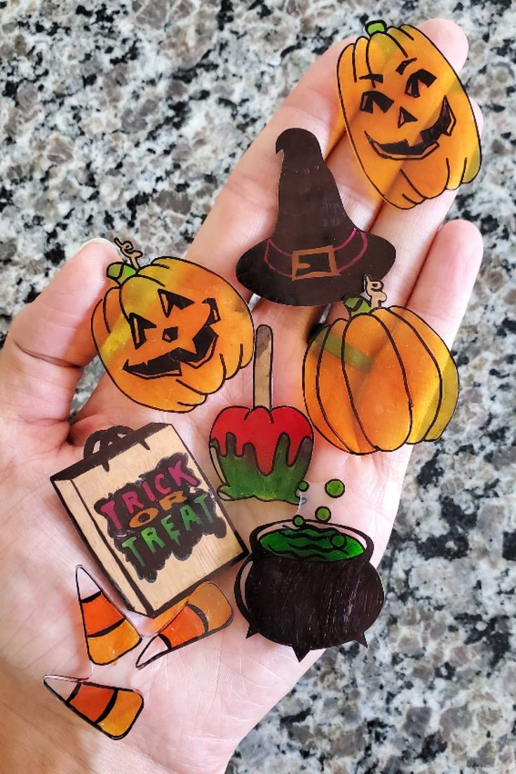 a person is holding up some halloween themed magnets on their palm and they are all decorated with pumpkins