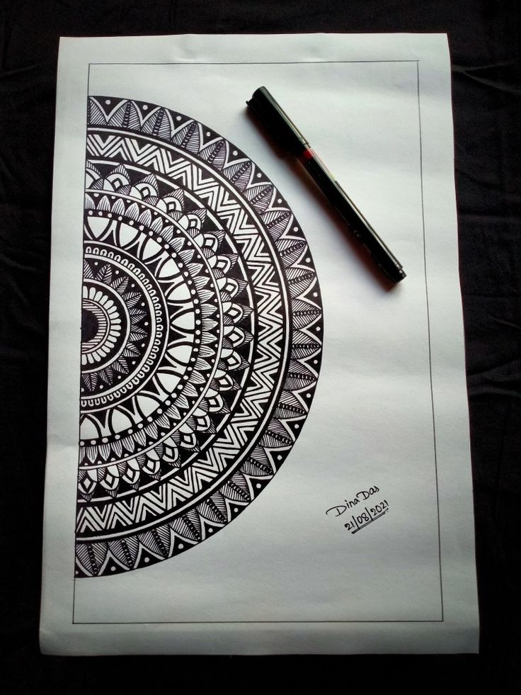 a black and white drawing with a pen on top of it next to a piece of paper