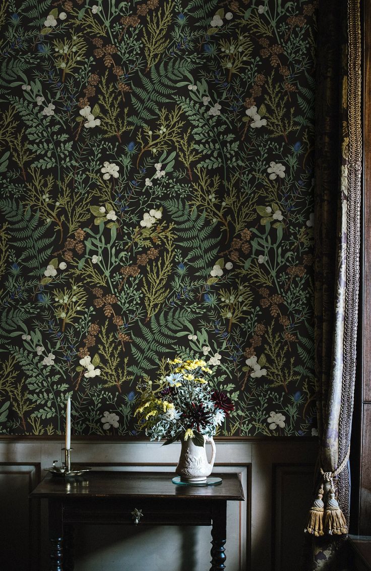 a vase with flowers sitting on top of a table next to a wallpapered wall