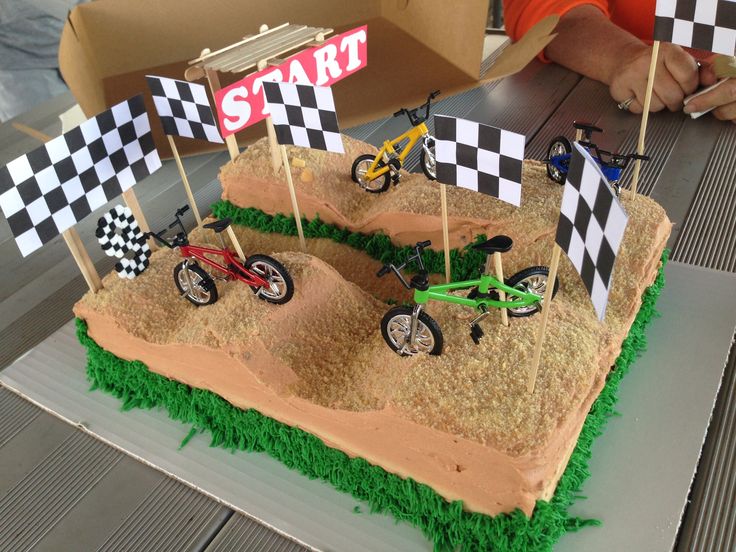 a birthday cake with dirt bikes and checkered flags on the top is ready to be eaten