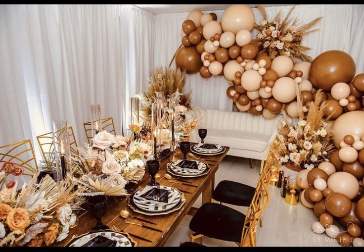 a dining room table set up for a party with balloons and flowers on the wall