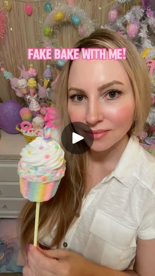 a woman holding a rainbow colored cake on a stick