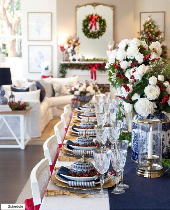 a dining room table set for christmas with blue and white plates, silverware and flowers