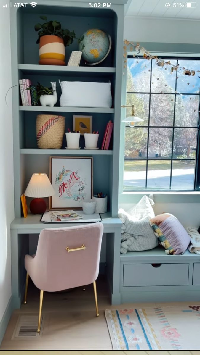 a blue bookcase filled with lots of books next to a pink chair and window