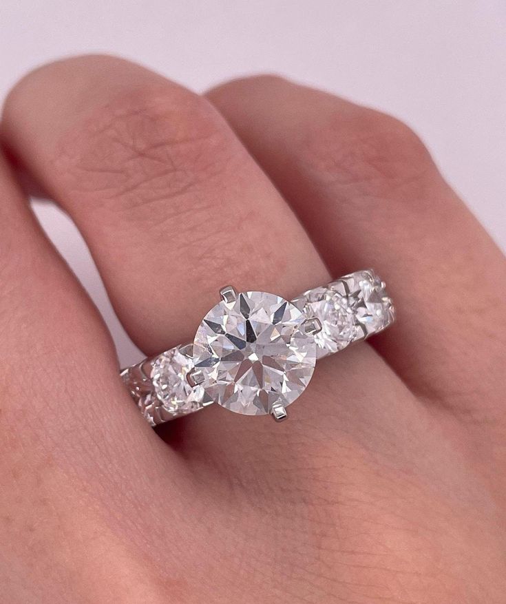 a woman's hand with a diamond ring on top of her finger and two diamonds in the middle