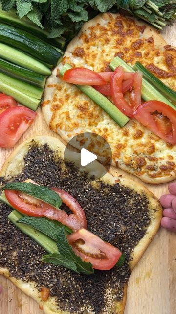 two pizzas with tomatoes, cucumbers and other vegetables on top of them