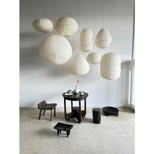 a room filled with lots of white paper lanterns hanging from the ceiling over a table