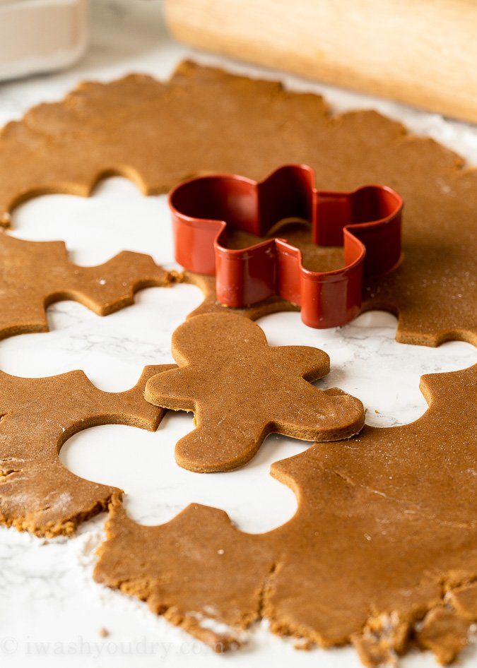 gingerbread cookies with cookie cutters laying on the counter next to them, ready to be baked