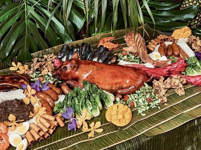 an assortment of meats and vegetables on a platter with palm leaves in the background