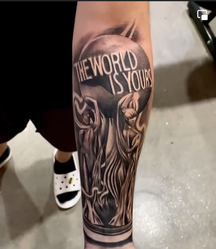 a man with a tattoo on his leg that says the world is yours