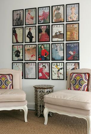 two white chairs sitting next to each other in front of pictures on the wall