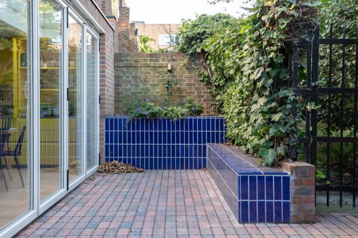 a brick patio with blue planters on the side and an iron fence around it