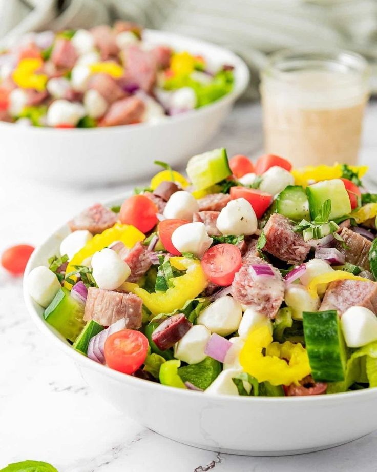 two white bowls filled with salad on top of a table