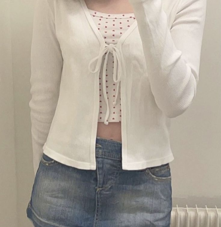 a woman taking a selfie in front of a mirror wearing a white cardigan