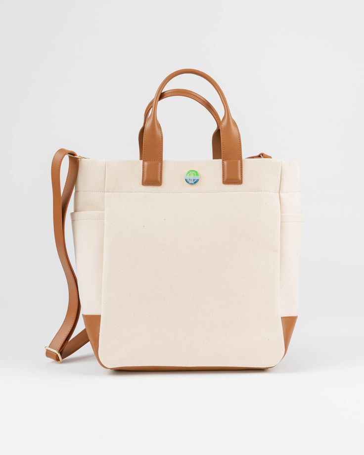 The Cape Code Tote is a truly elevated and refined take on the classic design. The design featured dual handles and a detachable strap for convenience. The spacious interior will fit all your daily needs and even works as a weekender or picnic bag. The streamlined style complements any outfit and works for his, hers, and theirs. • Natural/Saddle • 100% cotton with leather trim • Unlined • Two exterior side pockets • Leather bottom • Detachable & adjustable strap • 6” handle drop • Measures 11.5” Everyday Weekender Bag With Top Handle And Adjustable Strap, Everyday Travel Bag With Double Handle, Weekender Bag With Double Handle For Everyday Use, Everyday Travel Bag With Top Handle And Leather Details, Coated Canvas Weekender Bag With Adjustable Strap, Modern Weekender Tote Bag With Adjustable Strap, Weekender Bag With Leather Handles And Double Handle, Everyday Coated Canvas Weekender Bag With Double Handle, Rectangular Weekender Bag With Detachable Strap For Everyday Use